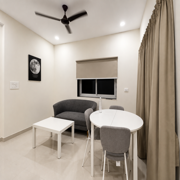 Living room, modern living room, minimalist interior, contemporary home, cozy seating area, gray sofa, gray armchair, dining table, round dining table, white table, dining chairs, coffee table, white coffee table, neutral colors, beige walls, beige curtains, floor-to-ceiling curtains, window, roller blind, ceiling fan, recessed lighting, wall art, moon artwork, lunar poster, tiled floor, bright interior, clean design, simple decor, elegant furniture, compact living space, apartment interior, residential interior, open space, functional layout, modern furniture, Scandinavian style, neutral palette, soft lighting, comfortable seating, home decor, interior photography, stylish living room, dining area, lounge area, contemporary decor, spacious room, window treatment, cream interior, gray upholstery, white furniture, modern apartment.